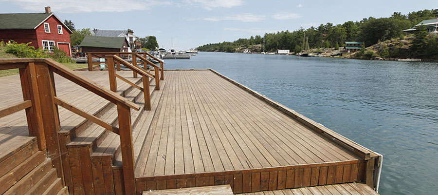 Close up image of a water front deck with a view of the water and buildings in the background.